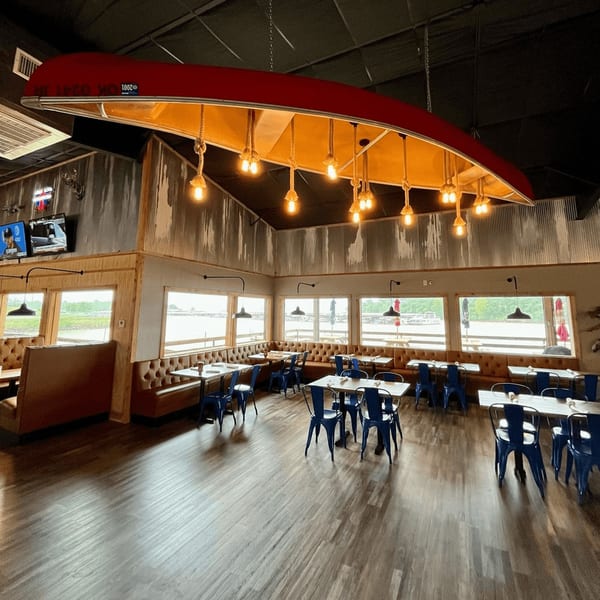 Captain John's dining room with a red canoe light fixture, blue chairs, and window views.