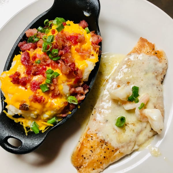 Captain John's seafood dish with fish in cream sauce and a side of loaded mashed potatoes.