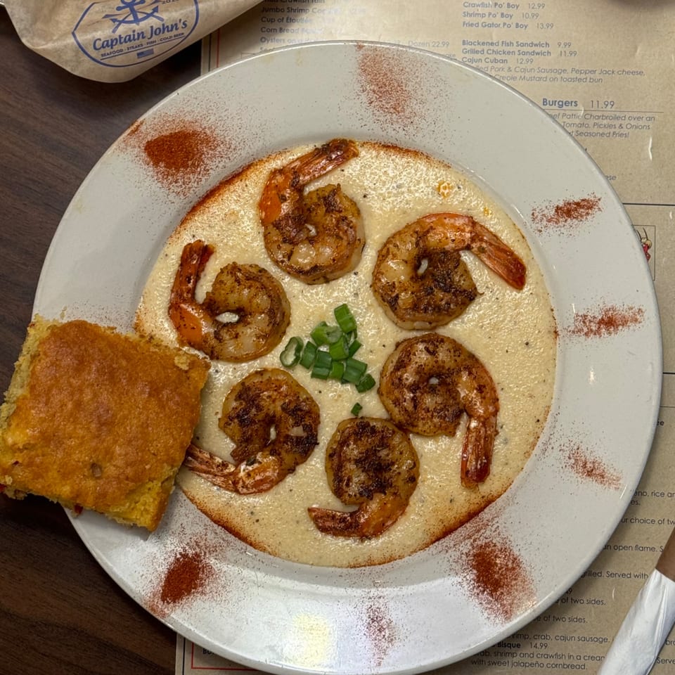 Captain John's shrimp and grits with cornbread, garnished with green onions and paprika.