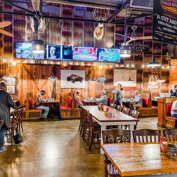 Rustic Captain John's interior with patrons dining at tables and booths, TVs, and mounted animal heads.